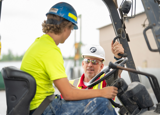 County Materials supervisor training a new student team member on forklift operation.