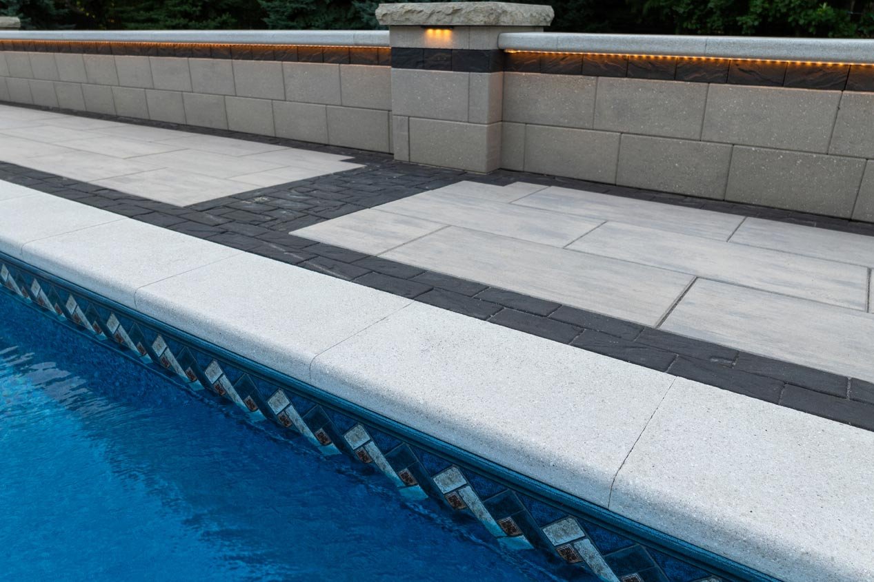 A low seat wall built with concrete wall blocks adds seating near the edge of a backyard swimming pool.