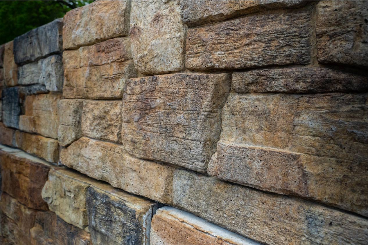 Close-up of a retaining wall made with precast modular block and stained after installation to look like natural stone. 